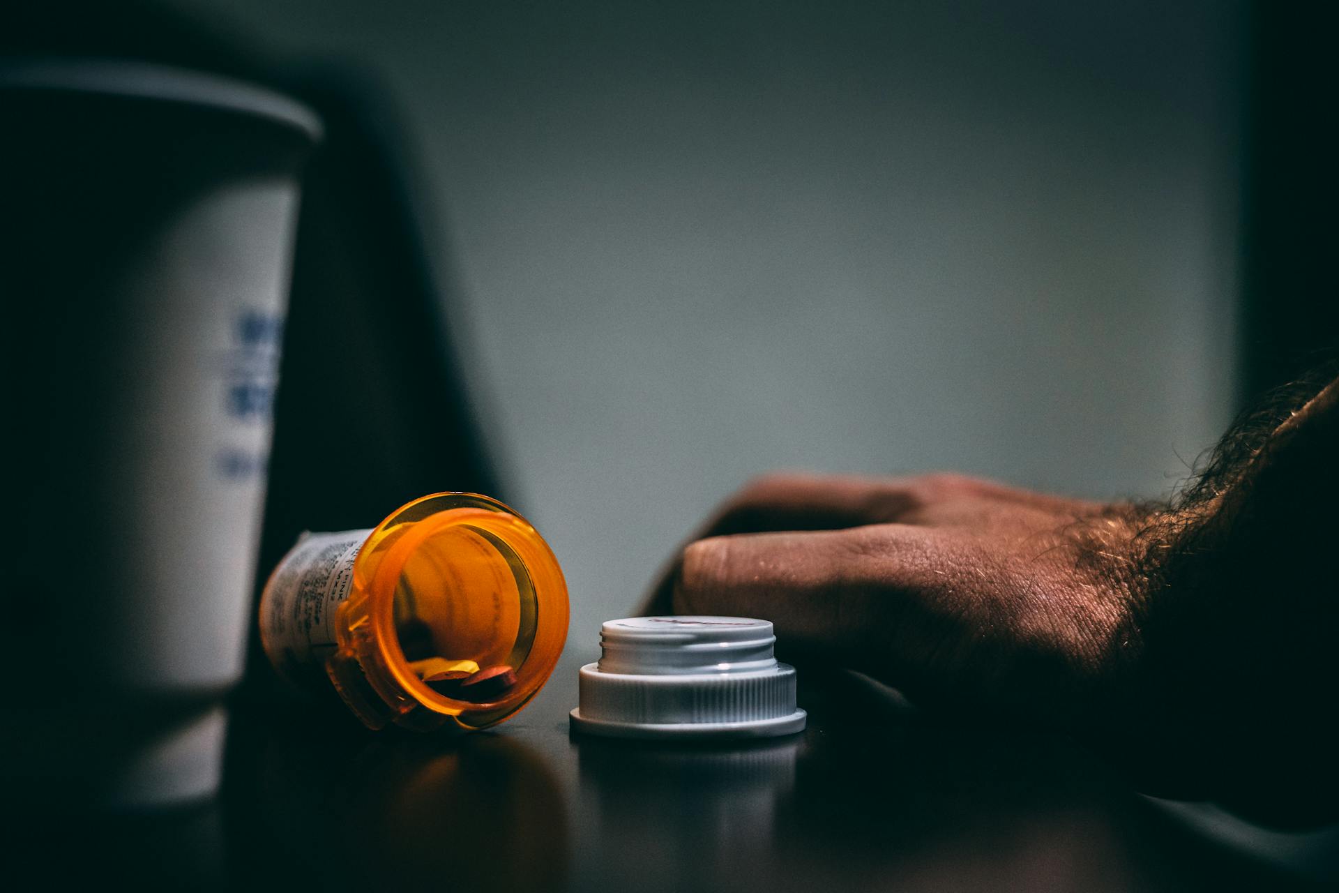 a high functioning addict with a hand next to a bottle of pills