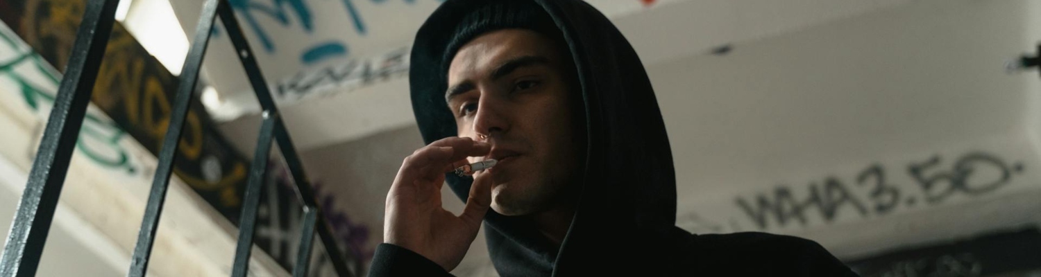 a man with a hood smoking a cigar