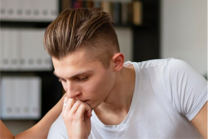 A man in therapy for overcoming anger and addiction leans his chin on his hand